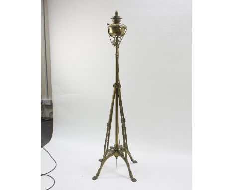 A brass standard lamp in the manner of WAS Benson, with oil well to top, connected for electricity, 157cm high, together with