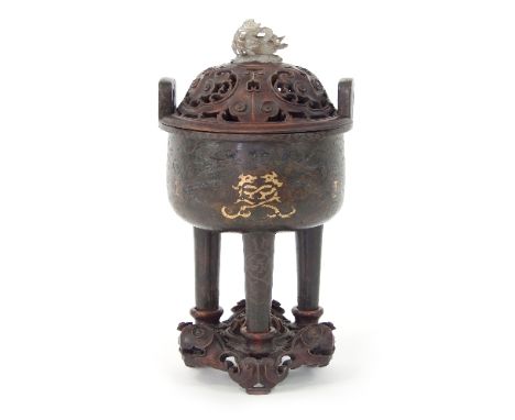 A Chinese bronze ding incised in gold and silver with dragons and scrolling designs, raised on three tapering legs, the carve