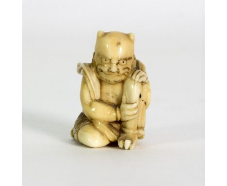 A Japanese carved walrus ivory figure of a squatting Oni, Meiji period, modelled applying moxa to an ulcer on his leg and a J