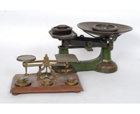 A good pair of mahogany and brass postal scales together with a cast iron painted green pair of grocer scales, both having we