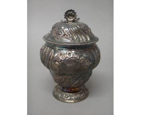 A George II silver sugar vase and cover, gilt within, the body embossed with floral sprays between spiral fluted bands and ra