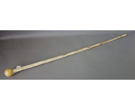 A whale bone walking stick, late 19th century, of cylindrical tapering form, with a spherical ivory pommel, 82.5cm long.