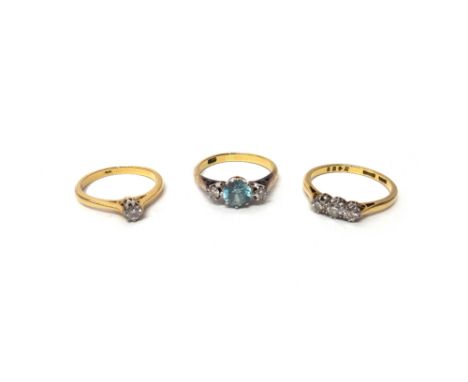 A gold, diamond and blue zircon set three stone ring, claw set with the circular cut blue zircon at the centre, detailed 18 C