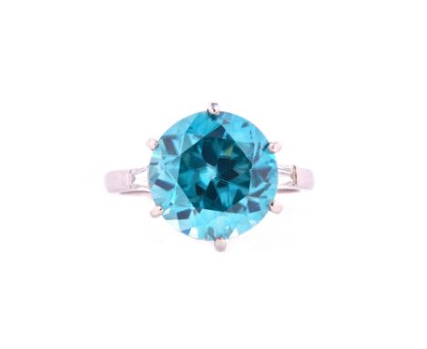 A blue zircon and diamond ring, claw set with the circular cut blue zircon at the centre between tapering baguette diamond si