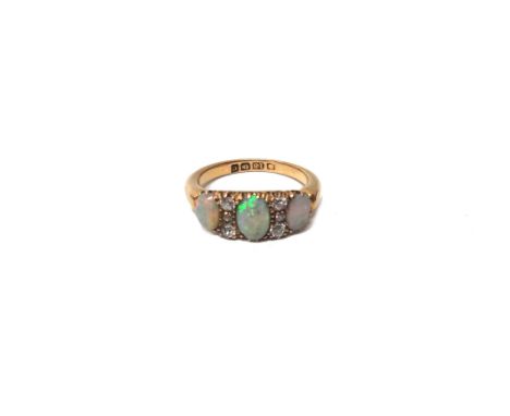 An 18ct gold, opal and diamond set ring, mounted with three oval opals and with two rows of cushion shaped diamonds mounted a