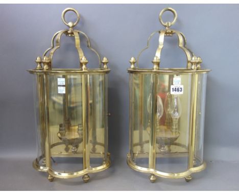 A pair of modern brass and glass wall lights, each with three shaped glass panels enclosing a two branch light fitment surmou