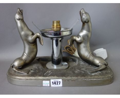 A white metal Art Deco table lamp cast with two opposing seals, a figural Art Deco table lamp, and one further cast with a st