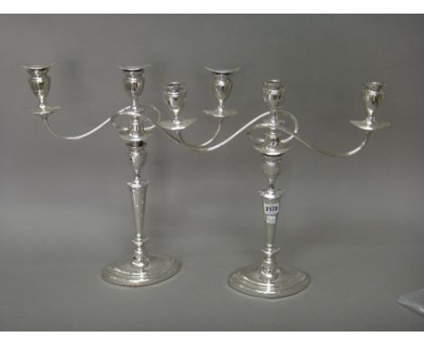 A pair of plated three light table candelabra, each having fluted scrolling arms and raised on an oval base, in the early 19t