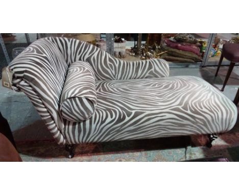 A 20th century chaise longue, with zebra print upholstery, on metal scroll supports.