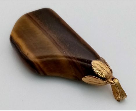 A 14 K yellow gold pendant with a large tiger's eye Length: 35 mm, weight: 6.6 g. 