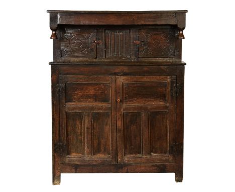 A 17th century joined oak court cupboard the three plank top with a plane frieze and twin finials over two carved cupboard do