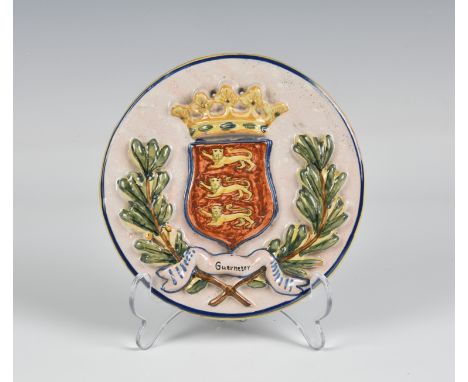 A Quimper HB 'Guernsey' circular plaque the plaque with raised Guernsey crest, two drill holes above crown, black 'HB' and nu