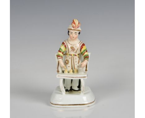 A 19th century Staffordshire porcelaneous figure of a Magician c.1830, the conjuror wearing a feathered turban, standing betw