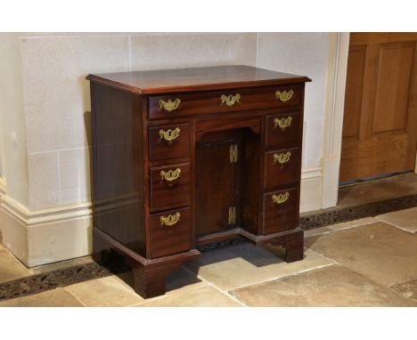 A George III mahogany kneehole desk the moulded top over a shallow full width drawer, the recessed kneehole beneath with a cu