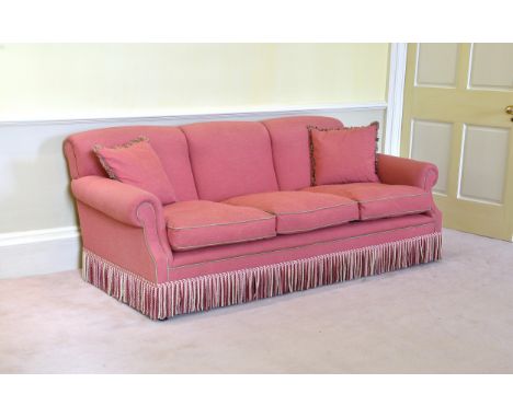 A Howard style three seater sofa late 20th century, in gold piped deep pink upholstery, with fringed edging, 84in. (213.5cm.)