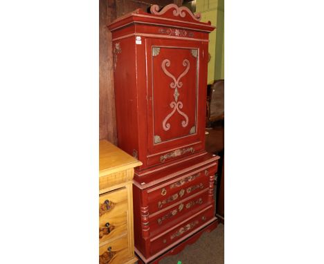 A late 19th century Danish red painted cabinet on chest, with scrollwork adorned pediment and single panel cupboard door, the