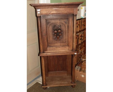 A 19th century Danish oak cabinet on stand, integral cornice, single door with carved fruit panel, column supports, undertier