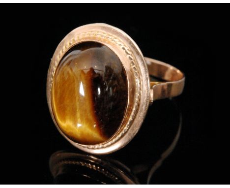 A 9ct hallmarked single stone tigers eye ring, collar set stone to rope twist border pierced shoulders, ring size R 1/2.  