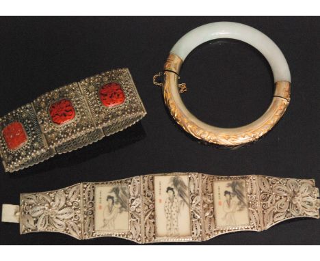 A Chinese jade and silver gilt hinged bangle, a Chinese cinnabar and white metal panel link bracelet and another similar five