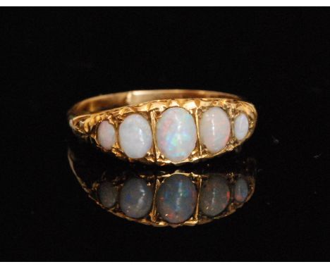 An early 20th Century graduating five stone opal boat shaped ring, oval stones to a scroll decorated head, ring size R. 