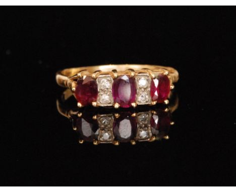 An 18ct ruby and diamond dress ring, three oval cut rubies each spaced by two brilliant cut diamonds, claw set within raised 