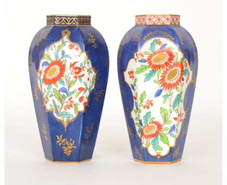 A pair of Royal Worcester hexagonal vases each decorated with cartouche panels of sprays of flowers against a blue ground wit