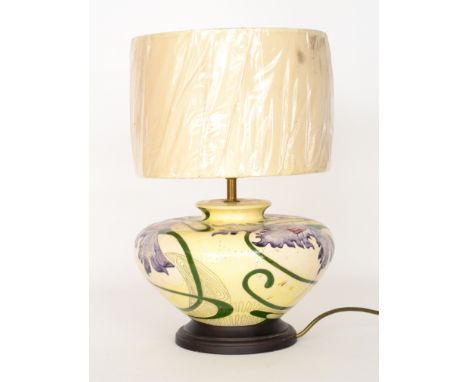 A Black Ryden Pottery lamp base of compressed form decorated with large purple flowers against a pale yellow ground, printed 