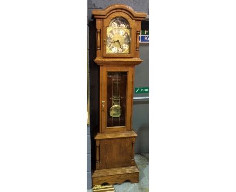 A reproduction oak longcase clock with eight-day movement, the 11" brass broken arch dial with corner spandrels, un-named, wi