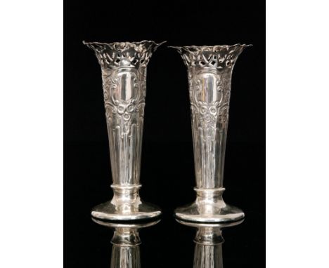 A pair of Edwardian hallmarked silver trumpet vases, plain circular bases below flaring foliate embossed bodies and pierced b