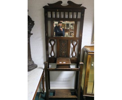 AN OAK FRAMED HALL STAND the rectangular back with bevelled plate and foliate carved panel the open base fitted with a single