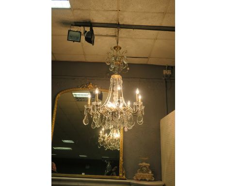 A CONTINENTAL STYLE GILT BRASS AND CUT GLASS EIGHT ARM CHANDELIER the scrolled arms hung with faceted chains and pendant drop