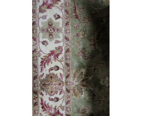 A WOOL RUG, the light green and beige ground with central floral panel within a conforming border,232cms x 160cms.
