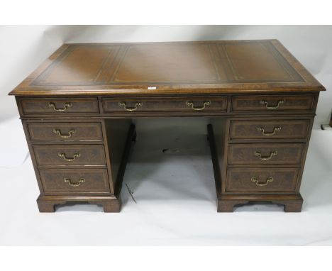 A GEORGIAN STYLE BURR WALNUT VENEERED AND LEATHER TOOLED KNEE HOLE DESK the rectangular top with moulded rim above a central 