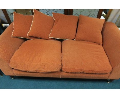 A MODERN UPHOLSTERED SOFA OF LARGE PROPORTIONS the orange upholstered frame with loose cushions on wooden turned supports wit