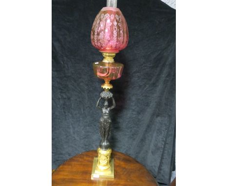 A VICTORIAN STYLE OIL LAMP the ruby glazed shade and reservoir supported by a black painted female on a gilded plinth base 10