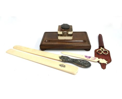 A c.1920s glass and silver topped inkwell set within mahogany inkstand; together with a Victorian bone folder with chased sil