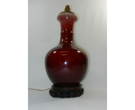 A large Chinese sang de beouf baulster vase, converted to a lamp on carved hardwood base, the vase 36cm high (not including s