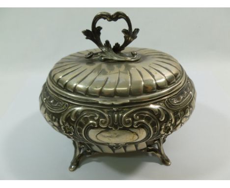 A 19th century German .830 standard silver tea caddy, raised on four acanthus scroll feet the body and lid with embossed deco