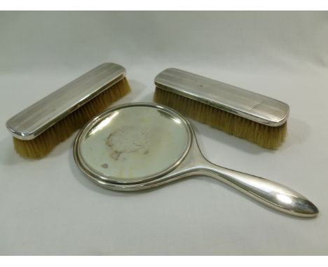 A silver backed hand mirror and two matching silver backed brushes, Chester 1919, with engine turned decoration CONDITION REP