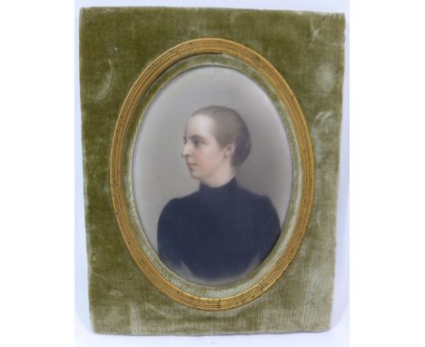 A late Victorian oval portrait miniature on porcelain of a woman, in a black dress, with gilt mount and green velvet frame, t