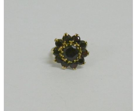 A 1960's large 9 carat garnet circular cluster ring, the 11 round mixed cut garnets in claw setting, London 1964, 5.5g gross,