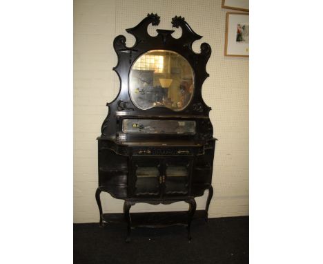 An Edwardian ebonised mirror backed vitrine, the broken scrolled pediment over trinket shelves around bevelled kidney and rec