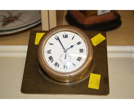 An early 20th century brass desk timepiece, fashioned as a ship's clock with eight day Swiss movement faced by enamel Roman a