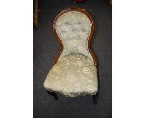 A Victorian walnut spoonback nursing chair, with florally carved rail, button upholstered back, overstuffed seat on French ca