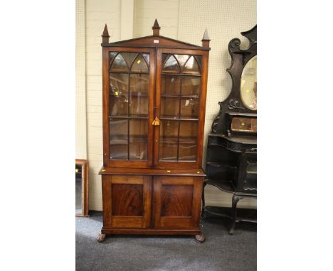 An early 19th century mahogany cabinet bookcase, the architectural pediment and steeple finials over a pair of navette barred