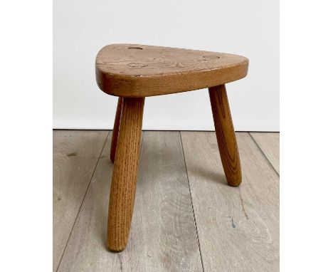 A Robin Nance elm milking stool, with triangular seat and three turned legs, stamped NANCE WORKSHOPS ST IVES, height 25cm.Con