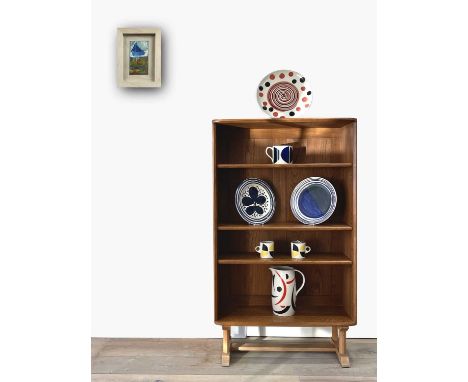 An Ercol pale elm floor standing low bookcase, with three adjustable shelves and raised on four supports united by stretchers
