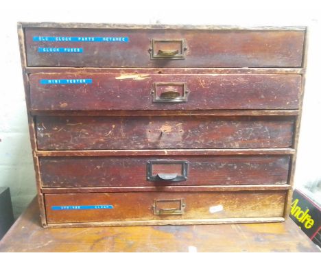 A five drawer horologist's chest and contents comprising watch and clock making spares.