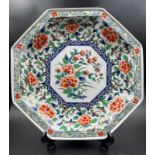 An Imari palette octagonal charger with a painted peony central shield and relief with gilt rim