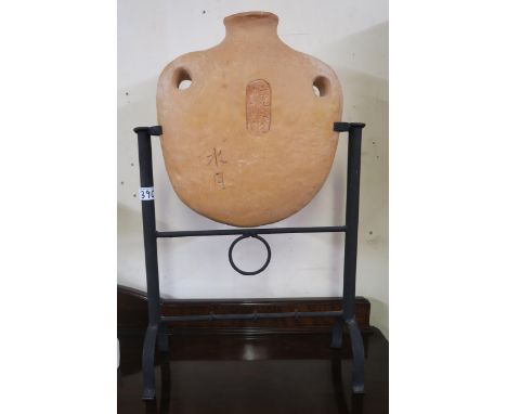 An Oriental terracotta flask on a contemporary wrought iron stand Condition Report:Available upon request